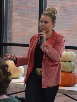 livestock judging team member with microphone and pumpkins on table in background
